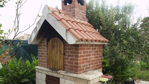 A brick-built outdoor structure with a tiled roof, a wooden door, and a small seating area. - Apartment in Slatine with Terrace, Air condition, WIFI, Washing machine (4784-3) (Slatine)