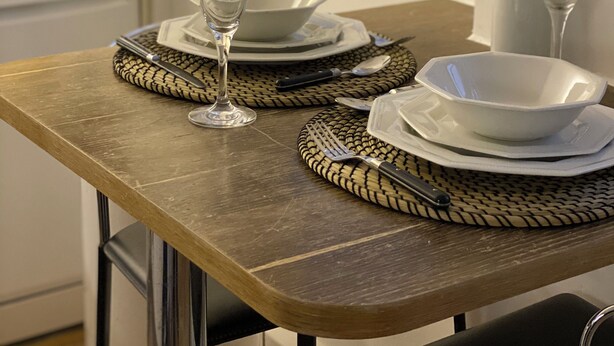 A dining table set with white plates, bowls, and cutlery, a glass, and a small potted plant. - Flat in the most desirable location in London - Kensington (London)