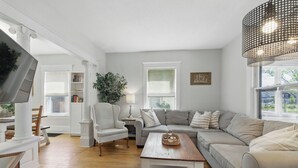 Una sala de estar moderna con un sofá modular, una mesa de centro de madera y un televisor grande.