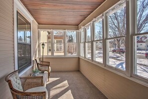 A sunroom with large windows, a wooden ceiling, and wicker furniture. - 5BR Farmhouse Near Allianz Field • Theater • Backyard (St Paul)