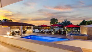 A pool area with lounge chairs and umbrellas, a bar, and a building with a tiled roof. - Villa Anela with pool in Porec, Istria (Buici)