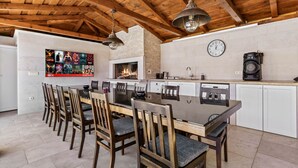 A kitchen with a large island, wooden ceiling beams, a fireplace, and a clock on the wall. - Villa Anela with pool in Porec, Istria (Buici)