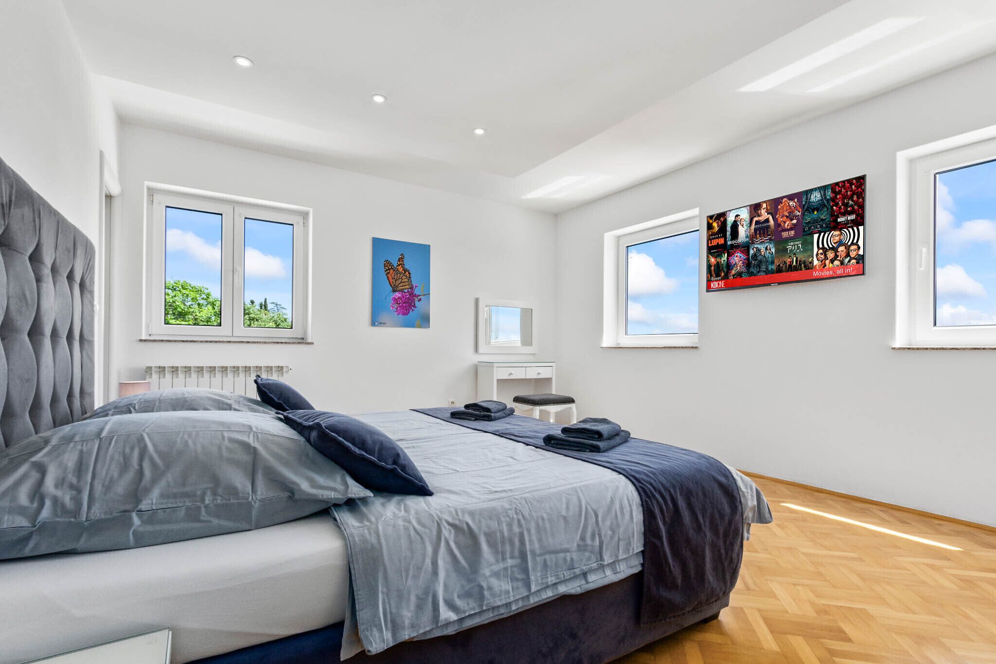 A modern bedroom with a bed, a desk, and a large window.