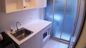 A modern kitchen with a stainless steel sink, white cabinets, and a window with frosted glass. - D condo Hyde Chiangrai. Authentic Thai hospitality. Room service is provided. (phan)