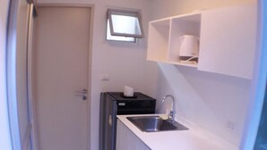 A compact kitchen with a sink, a microwave, and a small refrigerator. - D condo Hyde Chiangrai. Authentic Thai hospitality. Room service is provided. (phan)