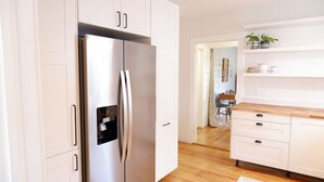 Eine moderne Küche mit weißen Schränken, einem Edelstahlkühlschrank und einer Holz Arbeitsplatte.