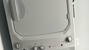 A front view of a white washing machine with control knobs and a start button.