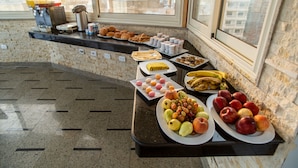 Un bufé de desayuno con diversas frutas, bollería y bebidas.