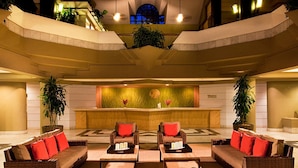 A lobby with a reception desk, two sofas with red cushions, and a large plant. - Family Friendly 3BR Villa in Paradise- Saturday March 26- Sat., April 4, 2026 (St. John)