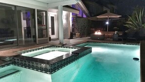 Ein Schwimmbad mit Whirlpool, umgeben von einer überdachten Terrasse mit Gartenmöbeln.