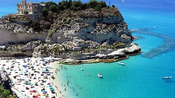 A coastal area with a beach, boats, and a building on a cliff. - B&B Il Tulipano - Rogliano (Calabria) Italy (Rogliano)