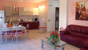 A modern living room with a glass coffee table, a red sofa, and a dining area with a table and chairs. - B&B Il Tulipano - Rogliano (Calabria) Italy (Rogliano)