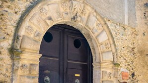 A stone building with a dark wooden double door, a small window above the door, and a stone wall with a plaque. - B&B Il Tulipano - Rogliano (Calabria) Italy (Rogliano)