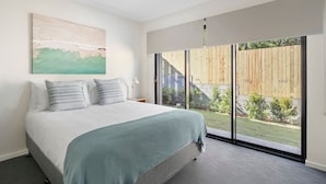 Un dormitorio con cama, ventana grande y vista al exterior.
