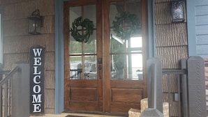 A wooden front door with a 'WELCOME' sign, a glass door, and a wreath.