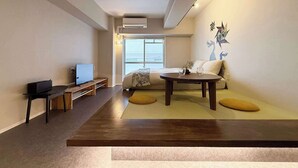 A modern living room with a sofa, coffee table, TV, and artwork on the wall. - ORIGAMINN 303 by b hotel - 5 mins PeacePark (Hiroshima City)