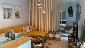 A modern living room with a yellow sofa, wooden accents, and a striped partition. - Modern and romantic house with large garden to relax (Ponta Delgada)