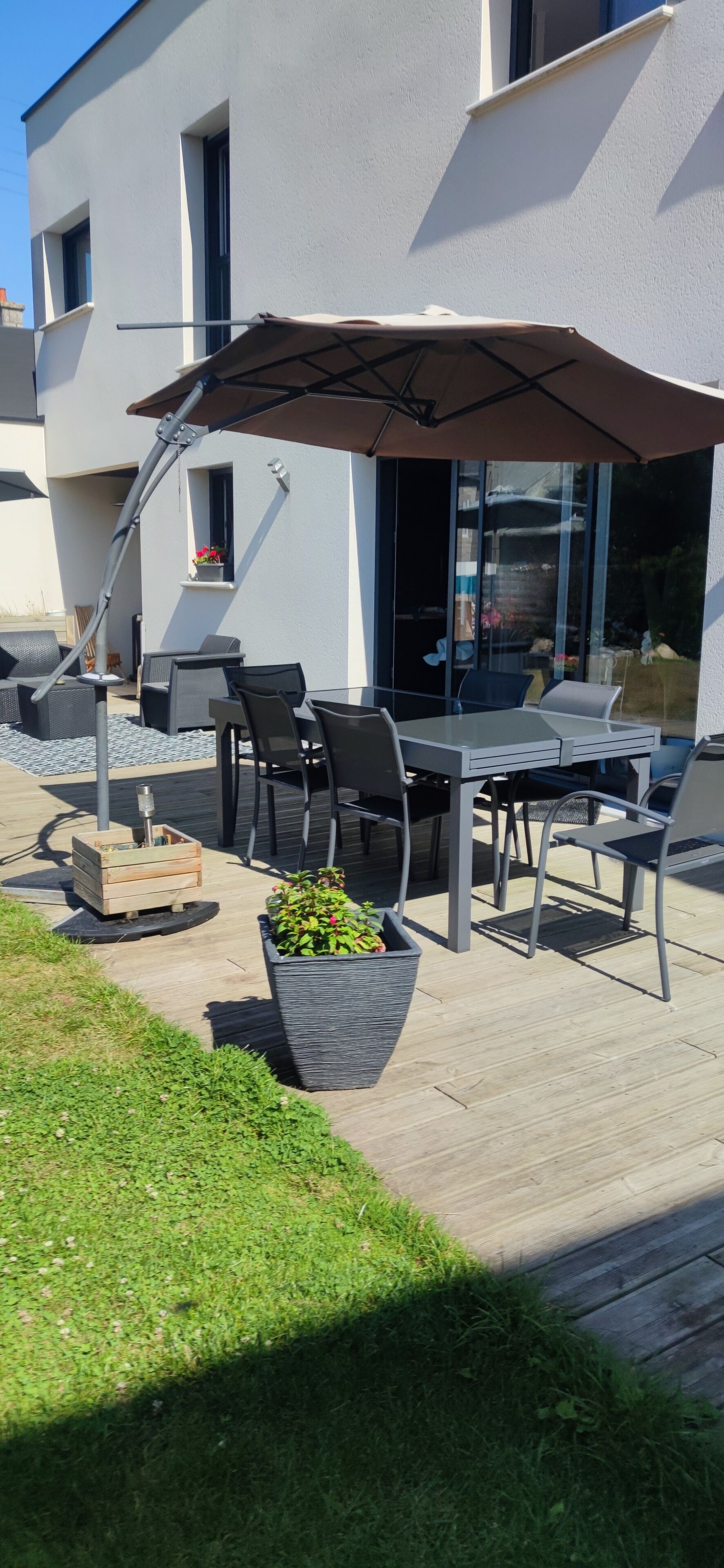 An outdoor patio with a table and chairs, a large umbrella, and potted plants.