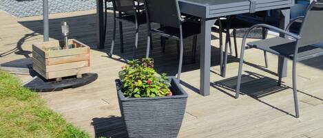 An outdoor patio with a table and chairs, a large umbrella, and potted plants.