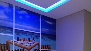 Un dormitorio con cama, mesita de noche, televisor y ventana grande con vista al océano.