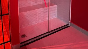 Una habitación moderna con un separador de vidrio, una pared de acento roja y una escalera visible.