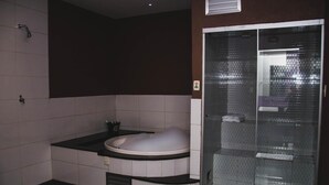 Un baño moderno con una bañera independiente, una ducha con mampara de vidrio y suelo de baldosas.
