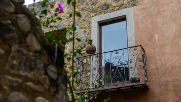 Un edificio de piedra con un balcón que presenta barandillas de hierro decorativas y una ventana.