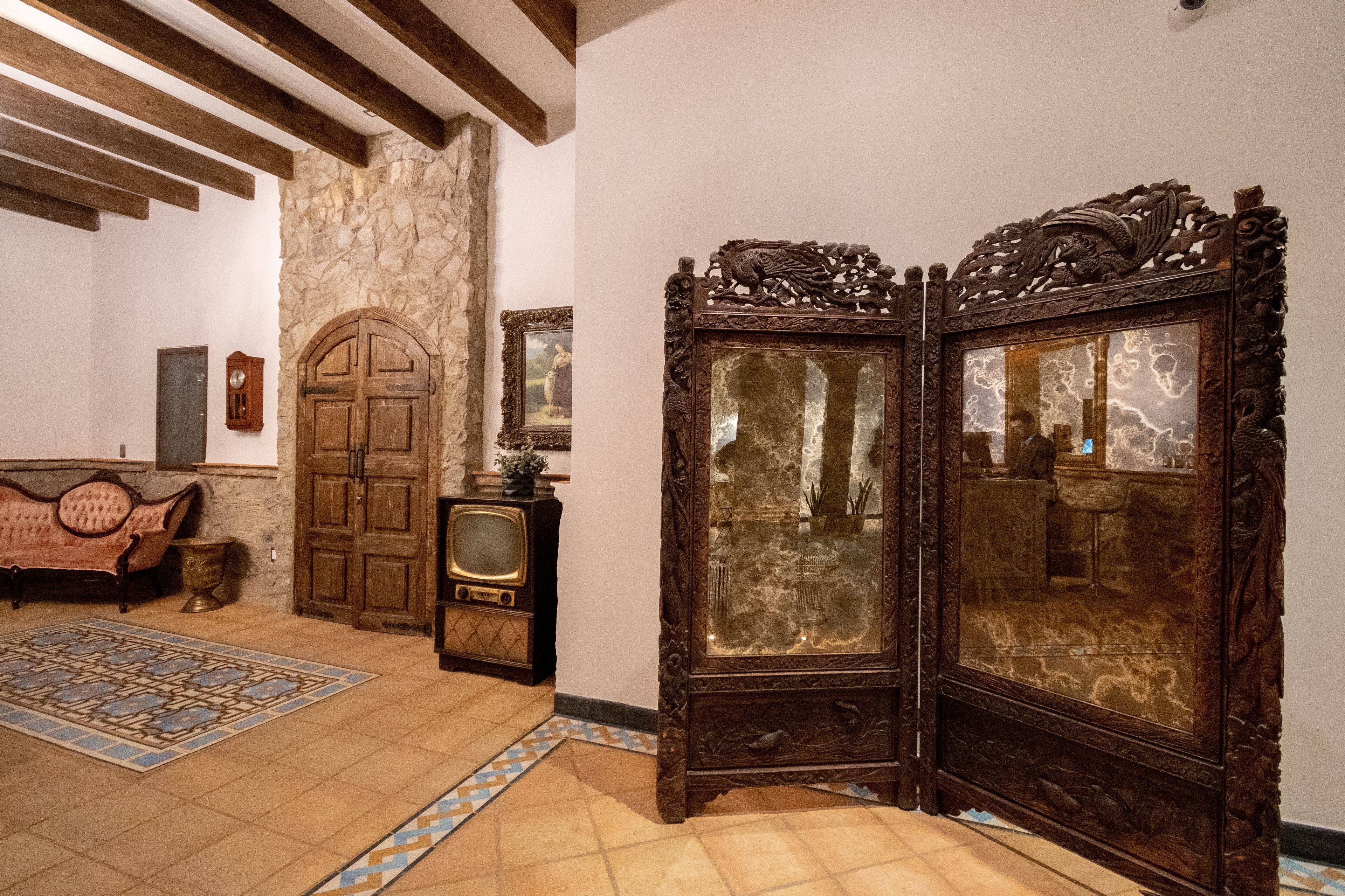 A room with a stone wall, wooden door, vintage television, and a decorative cabinet.