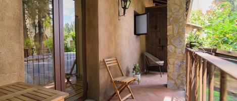 A wooden bench, a stone wall, and a potted plant on a patio.