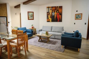 A living room with a grey sofa, blue armchairs, a glass coffee table, and wooden flooring. - Villa Toscana ValQuirico Hotel Boutique (Santeagueda)