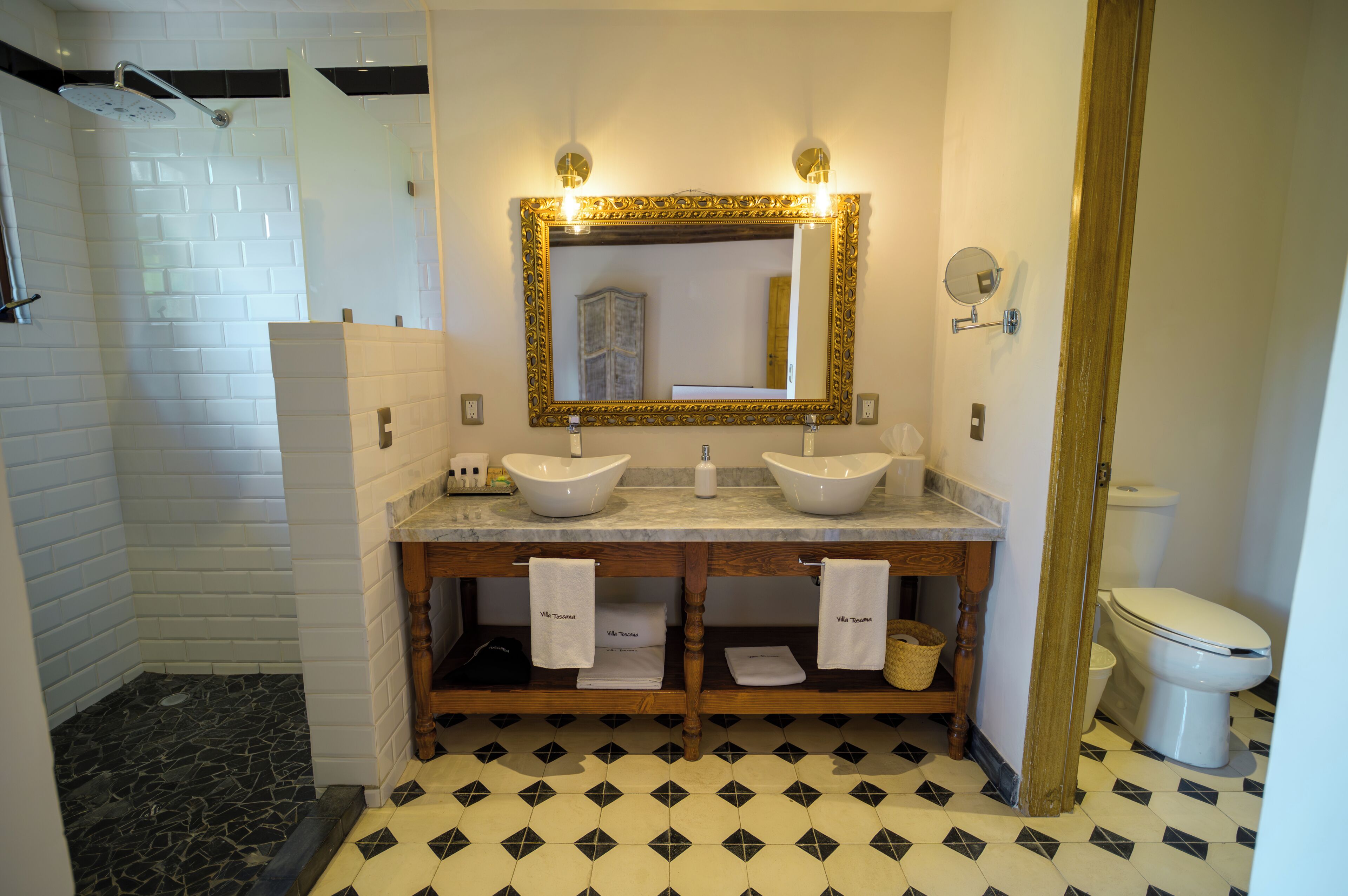 A bathroom with two sinks, a shower, and a toilet.