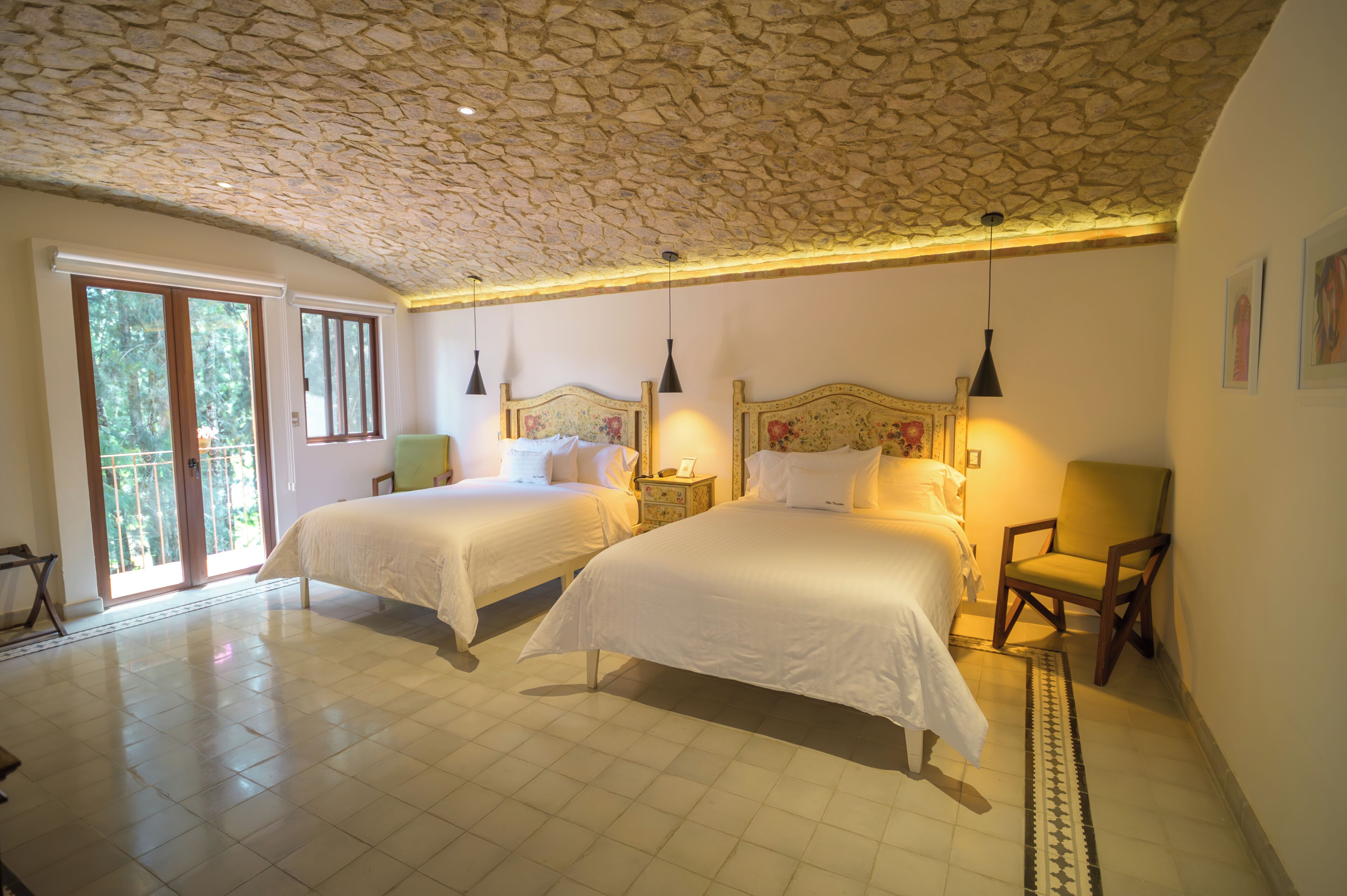Een slaapkamer met twee bedden, een stenen plafond en uitzicht op de omgeving.