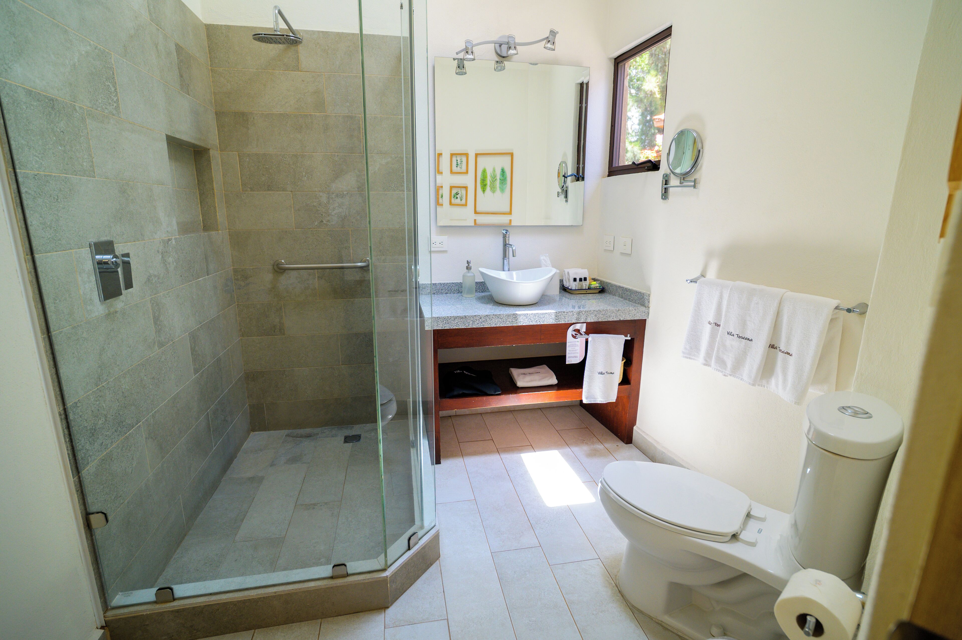Un baño con ducha de vidrio, lavabo, inodoro y espejo.