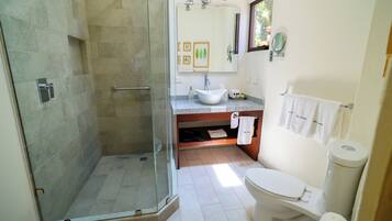 Un baño con ducha de vidrio, lavabo, inodoro y espejo.