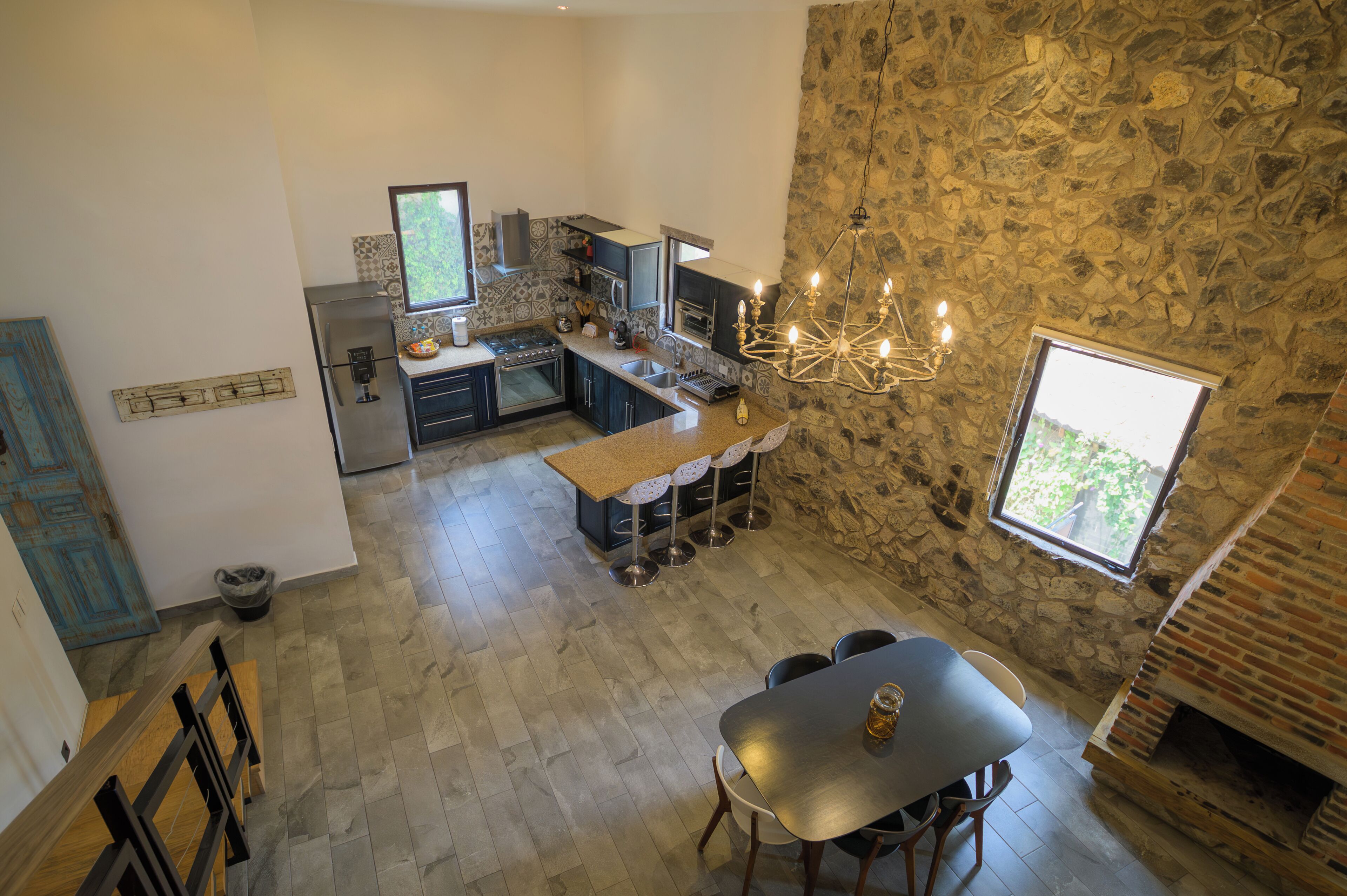A spacious kitchen with a stone wall, a large window, and a dining area with a table and chairs.