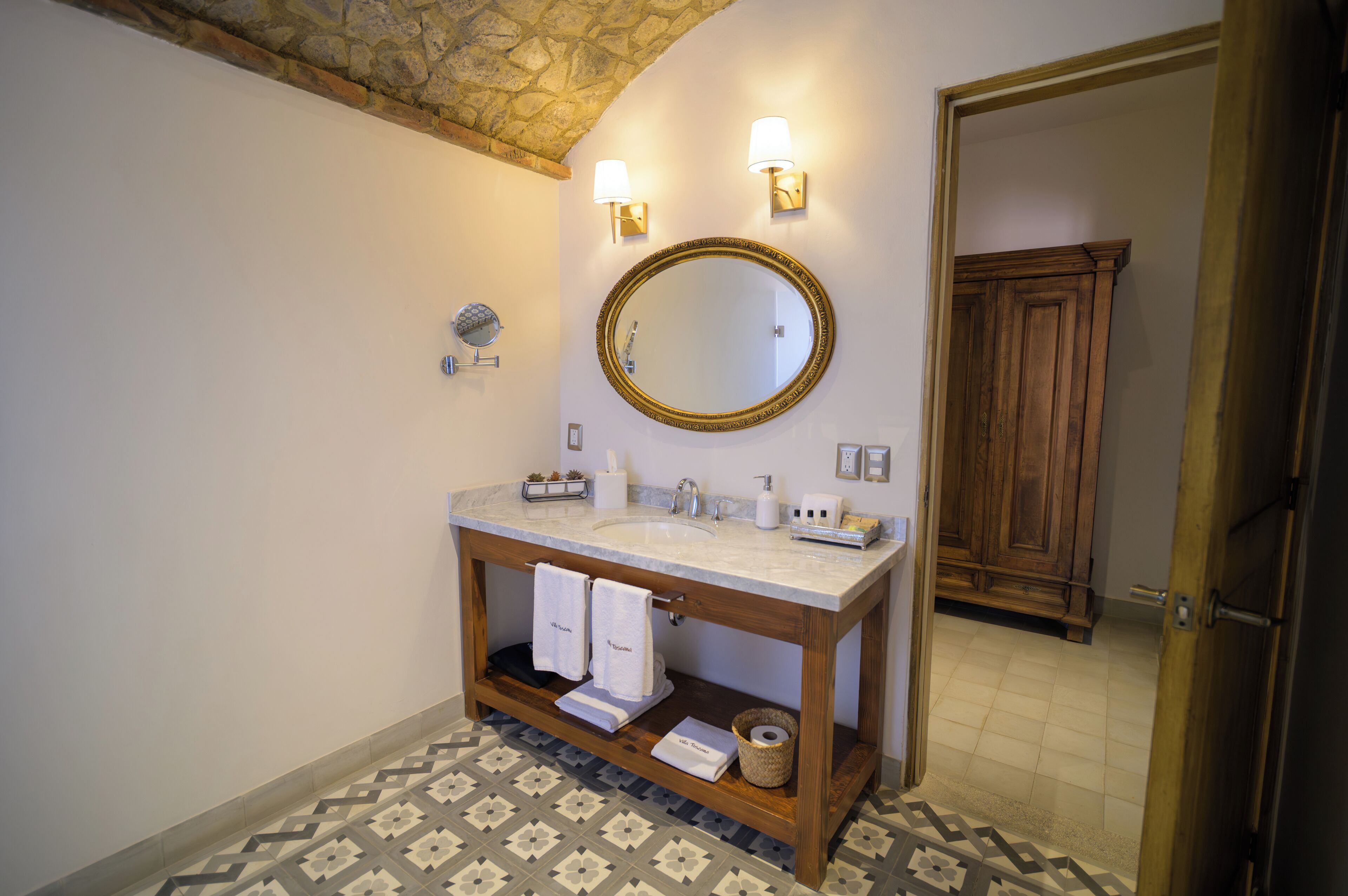 A bathroom with a marble sink, two wall-mounted lights, a large mirror, and a wooden vanity.