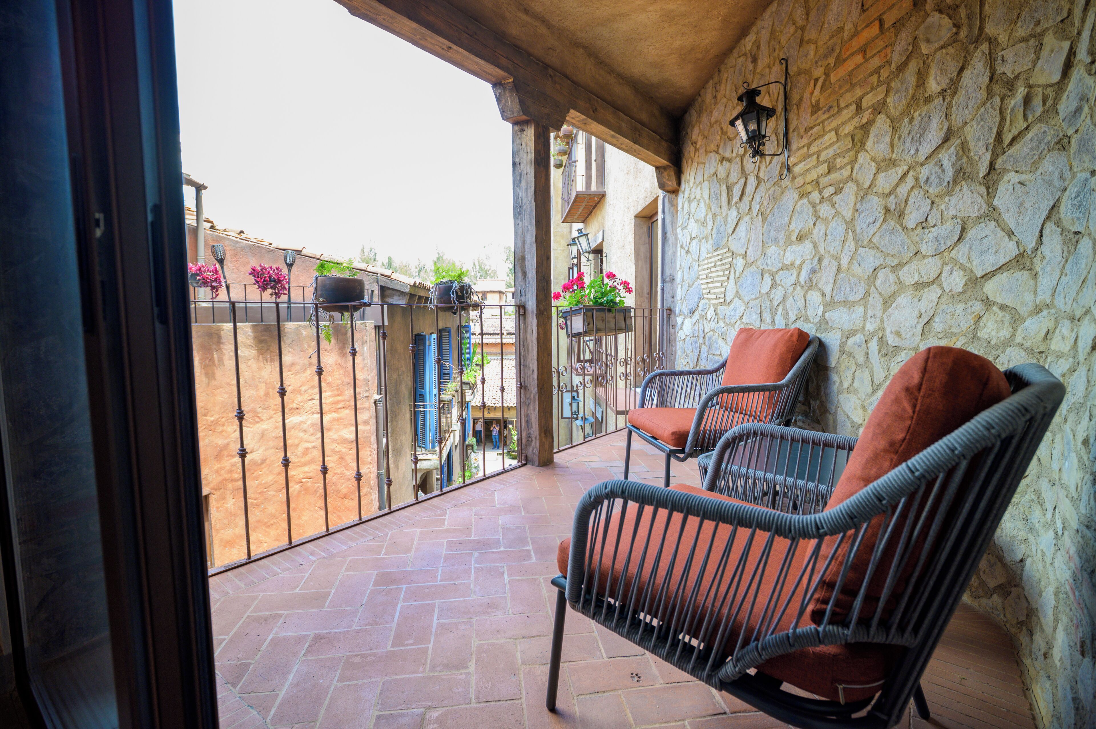 A balcony with wicker chairs and a stone wall.