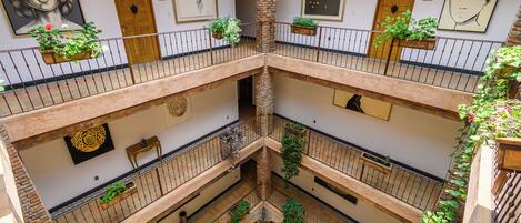 Un atrium à plusieurs niveaux, doté de balcons, de rampes en bois et de jardinières suspendues.