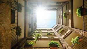 A sunlit atrium with a central skylight, wooden benches, and hanging planters.