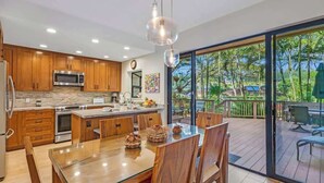 Une cuisine moderne avec des meubles en bois, des appareils électroménagers en acier inoxydable et une table à manger en verre.