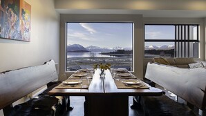 A dining area with a view of mountains and a lake, a painting on the wall, and a modern interior design. - Ranginui at Lake Tekapo (Lake Tekapo)