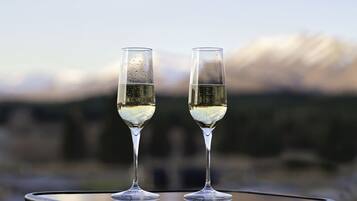 Dos copas de vino blanco sobre una mesa redonda con un fondo montañoso desenfocado.
