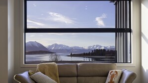 A room with a large window offering a view of mountains and a lake. - Ranginui at Lake Tekapo (Lake Tekapo)