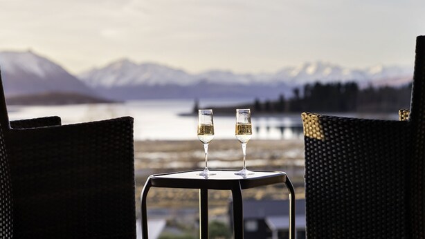 Two glasses of white wine on a small table with a view of mountains and a lake. - Ranginui at Lake Tekapo (Lake Tekapo)