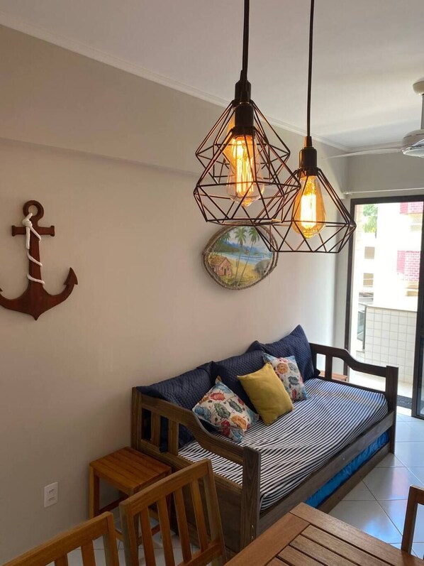 A cozy room with a wooden sofa, a dining table, and hanging light fixtures.
