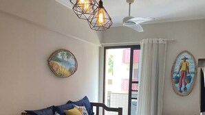 A dining area with a wooden table and chairs, a ceiling fan, and artwork on the walls.