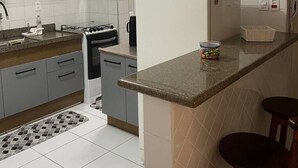 A modern kitchen with grey cabinets, a white refrigerator, and a countertop with a basket and a jar.