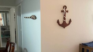 A room with a dining area, a wooden bench, and a wall-mounted anchor decoration.