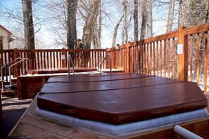 A wooden deck with a hot tub and a wooden bench.