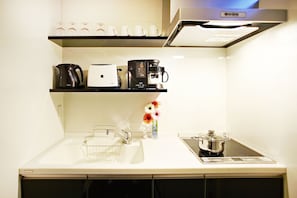 Enjoy cooking in this well-equipped kitchen with a stainless steel range hood, coffee maker, and kettle.